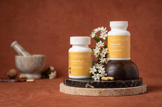 Celebrate META Multi GLP-1 Nutrition Support and META GC Metabolic Wellness bottles with white flowers on stone pedestals
